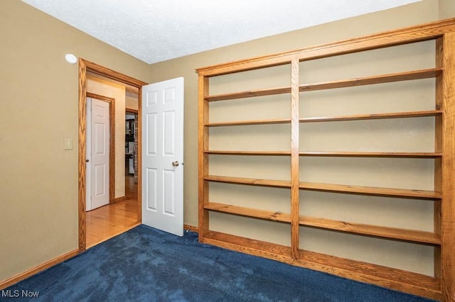 unfurnished bedroom featuring a textured ceiling and dark colored carpet