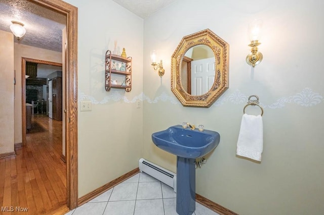 bathroom with sink, hardwood / wood-style floors, a textured ceiling, and a baseboard heating unit