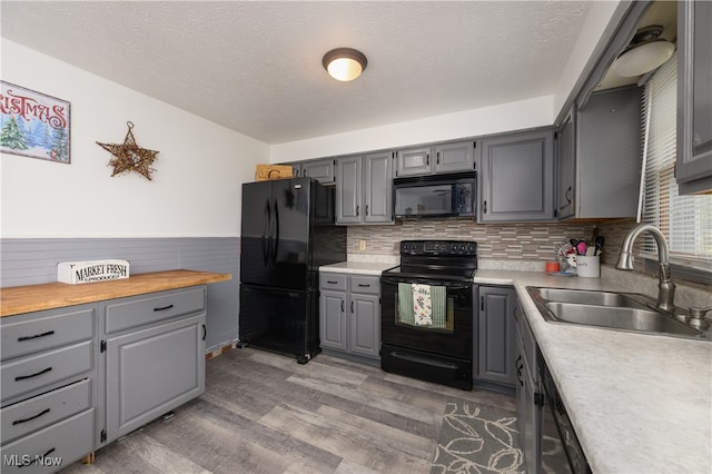 kitchen with hardwood / wood-style floors, sink, gray cabinets, and black appliances