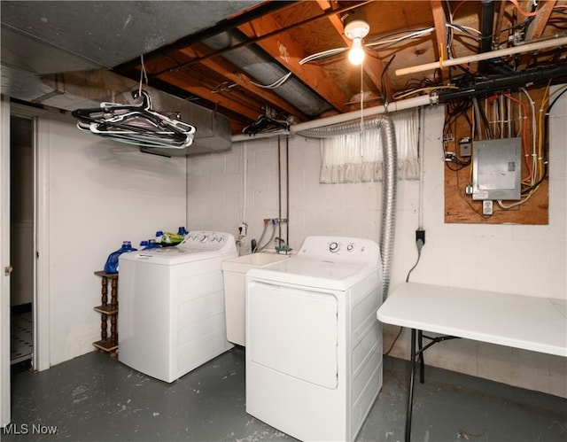 washroom featuring washing machine and dryer, sink, and electric panel