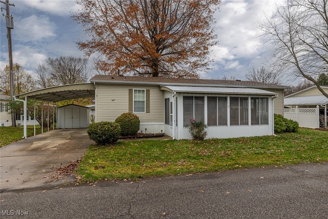 view of front of property featuring a storage shed, a sunroom, a front lawn, and a carport