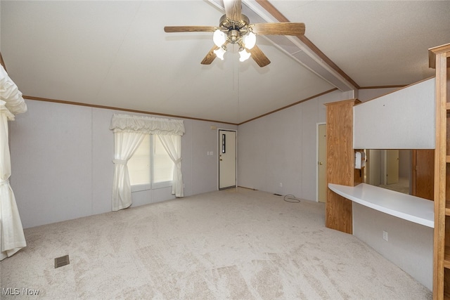 spare room featuring light carpet, vaulted ceiling with beams, ceiling fan, and ornamental molding