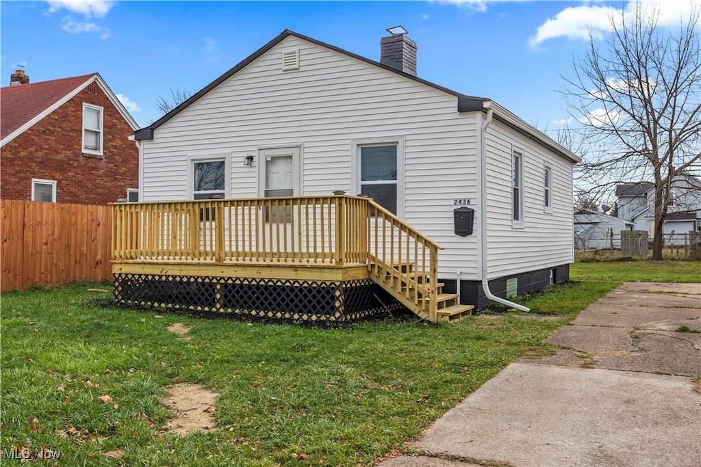 back of property with a lawn and a wooden deck