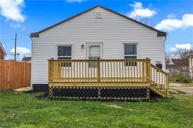 rear view of house featuring a lawn and a wooden deck