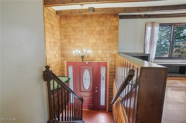 foyer entrance featuring beam ceiling and a notable chandelier