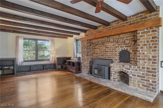 unfurnished living room featuring a wood stove, ceiling fan, beamed ceiling, and hardwood / wood-style flooring