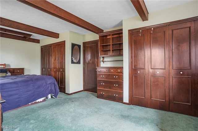 carpeted bedroom featuring beamed ceiling and a textured ceiling