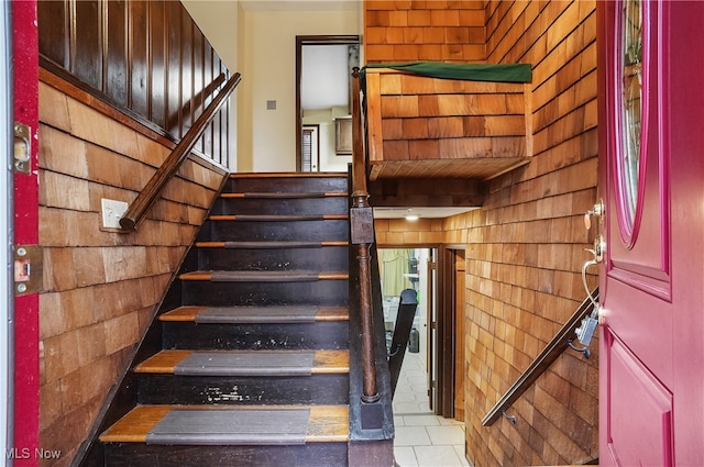 stairs featuring wood walls and tile patterned flooring