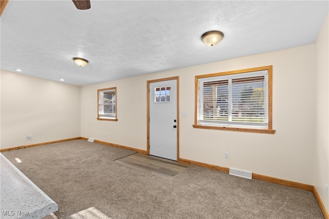 carpeted foyer with a textured ceiling