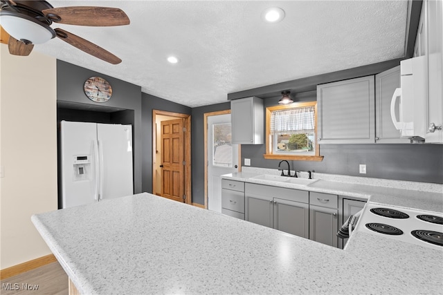 kitchen featuring gray cabinetry, sink, kitchen peninsula, a textured ceiling, and white appliances