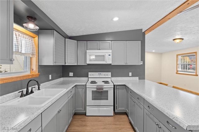 kitchen with lofted ceiling, gray cabinets, white appliances, and sink