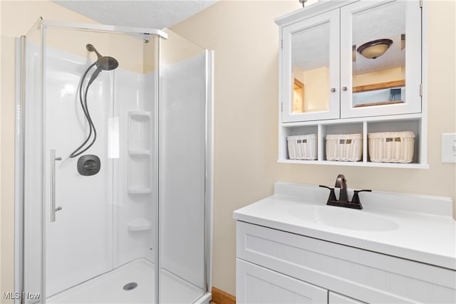 bathroom featuring vanity, a textured ceiling, and a shower with door