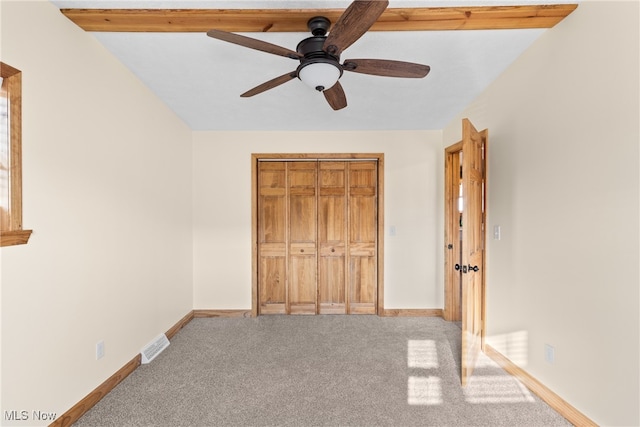 unfurnished bedroom with beamed ceiling, ceiling fan, light carpet, and a closet