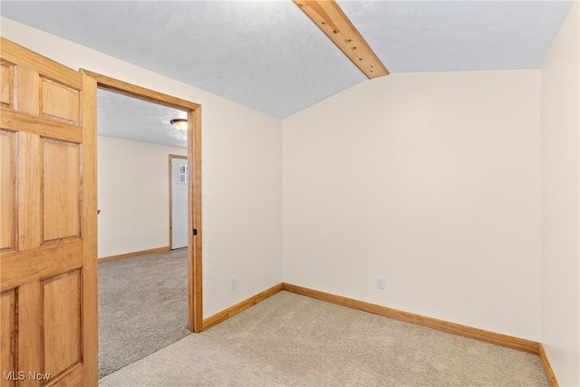 spare room with vaulted ceiling with beams, light colored carpet, and a textured ceiling