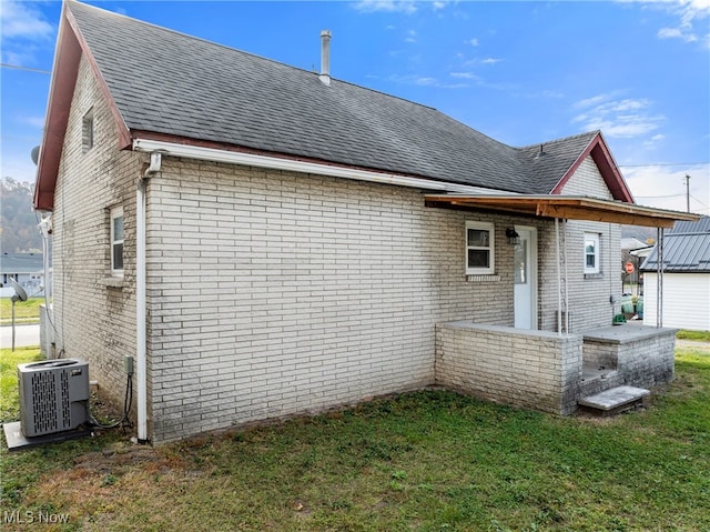 back of property featuring a lawn and central air condition unit