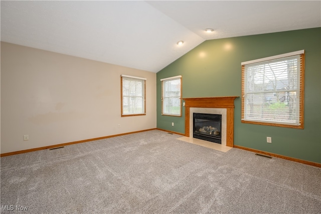 unfurnished living room with a healthy amount of sunlight, light carpet, and vaulted ceiling