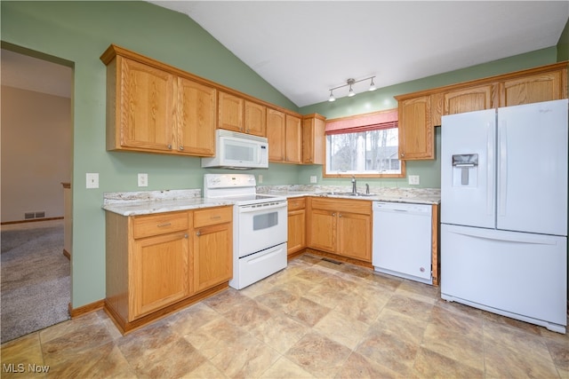 kitchen featuring white appliances, track lighting, sink, vaulted ceiling, and light stone counters