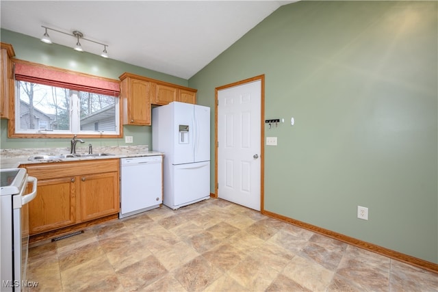 kitchen with white appliances, vaulted ceiling, and sink