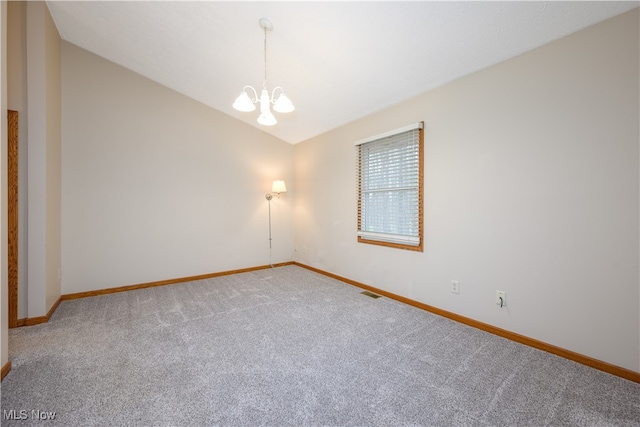 spare room featuring carpet flooring, a chandelier, and vaulted ceiling