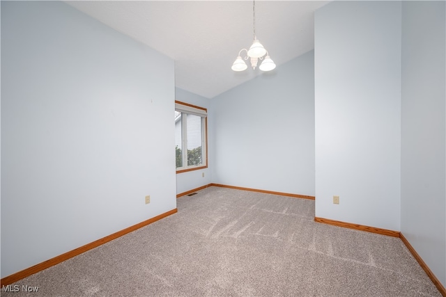 carpeted spare room with an inviting chandelier and lofted ceiling