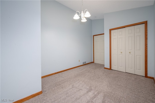 unfurnished bedroom with carpet flooring, a closet, and a notable chandelier