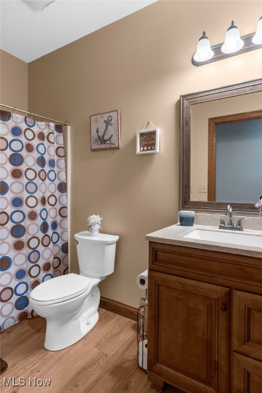 bathroom with wood-type flooring, vanity, and toilet