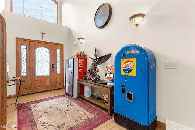 foyer with a healthy amount of sunlight, light hardwood / wood-style floors, and a high ceiling