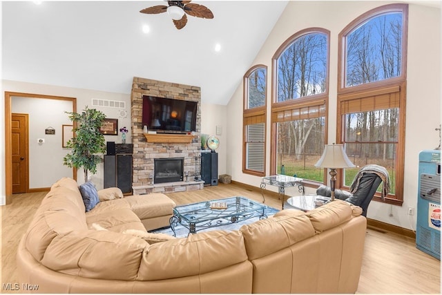 living room featuring ceiling fan, a fireplace, high vaulted ceiling, and light hardwood / wood-style flooring