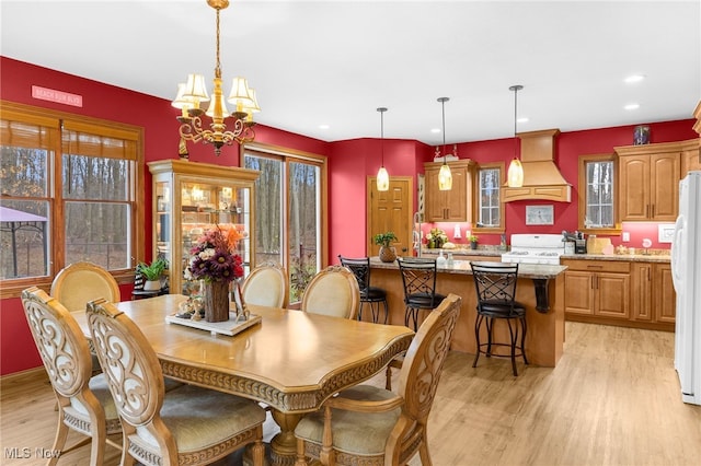 dining space featuring light hardwood / wood-style floors and an inviting chandelier