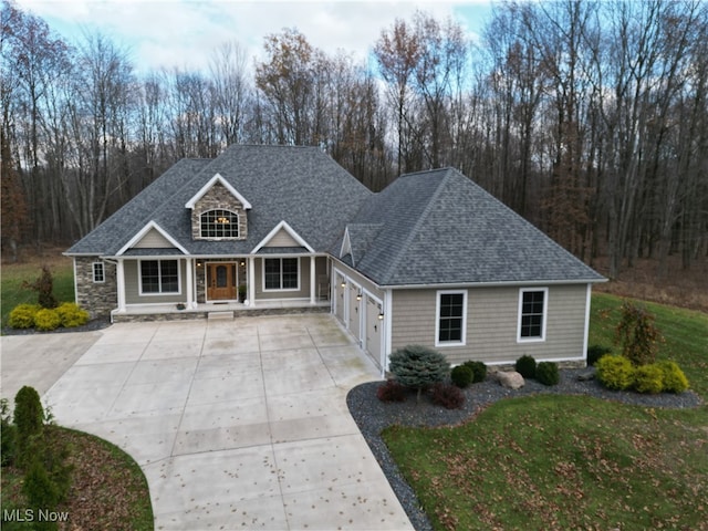 view of front of property featuring a porch, a garage, and a front lawn