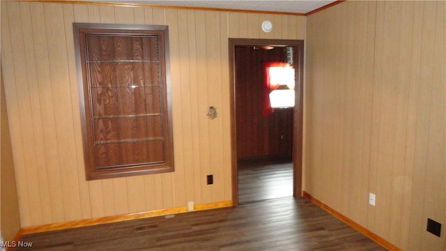 spare room featuring dark hardwood / wood-style flooring, ornamental molding, and wooden walls