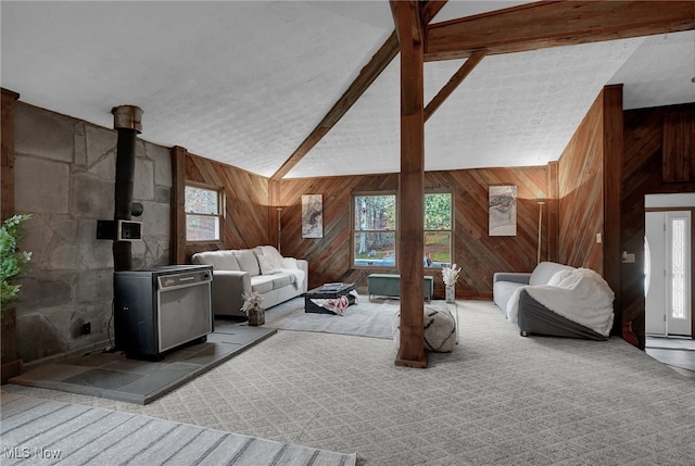 carpeted bedroom with wood walls, a wood stove, and beam ceiling