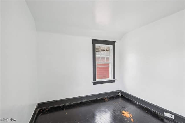 empty room with hardwood / wood-style flooring and vaulted ceiling