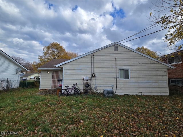 rear view of property with a lawn and cooling unit