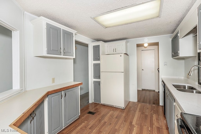 kitchen with gray cabinets, white refrigerator, sink, and a textured ceiling