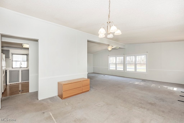 unfurnished room featuring a textured ceiling, crown molding, light colored carpet, and vaulted ceiling