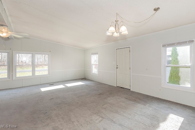 carpeted empty room with ceiling fan with notable chandelier, a textured ceiling, vaulted ceiling, and ornamental molding