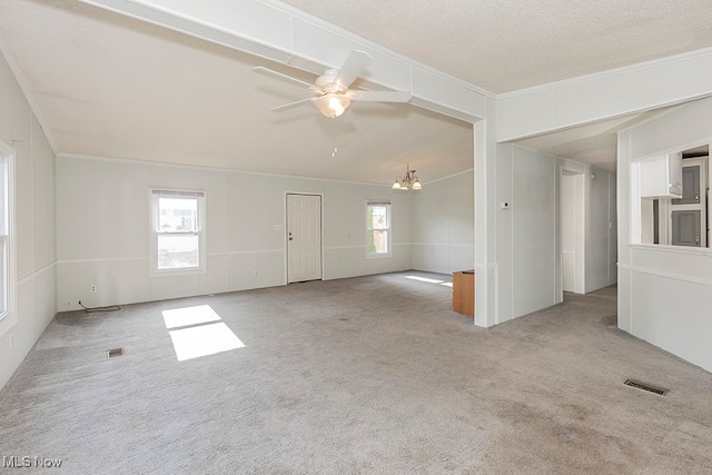 carpeted spare room featuring ceiling fan with notable chandelier, a textured ceiling, and ornamental molding