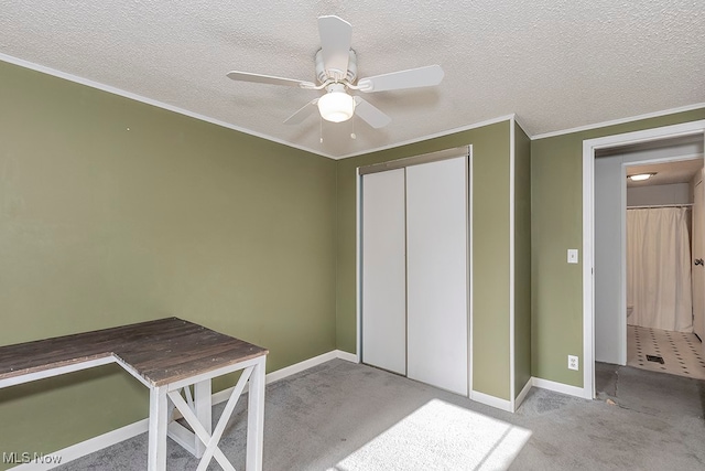 unfurnished office featuring ceiling fan, crown molding, light colored carpet, and a textured ceiling