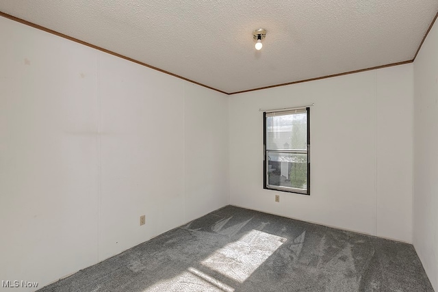 empty room featuring a textured ceiling, dark carpet, and crown molding