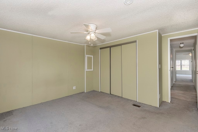 unfurnished bedroom with ceiling fan, light carpet, and a textured ceiling