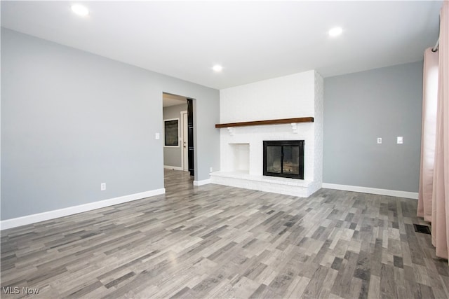 unfurnished living room with light hardwood / wood-style floors and a brick fireplace