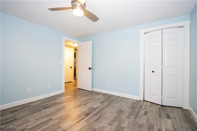 unfurnished bedroom featuring hardwood / wood-style floors, ceiling fan, and a closet