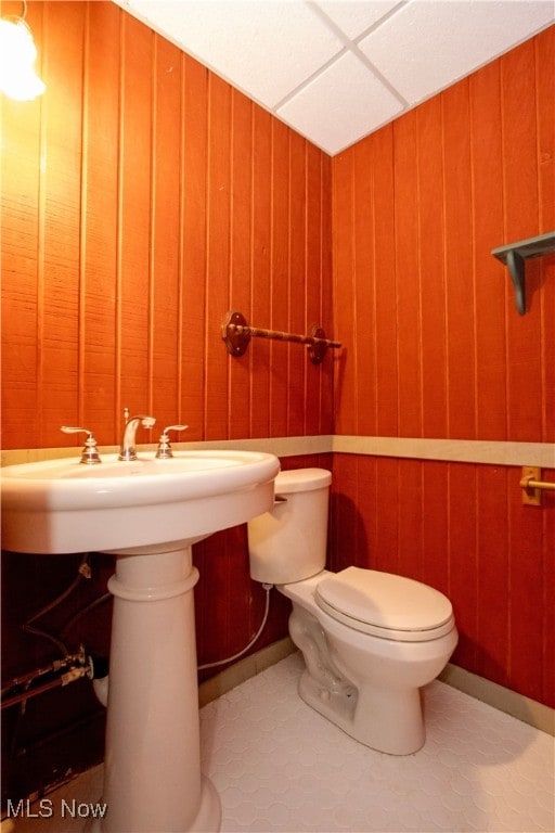 bathroom with wooden walls, tile patterned flooring, and toilet