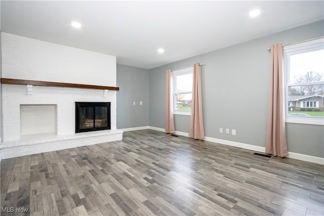 unfurnished living room featuring light hardwood / wood-style flooring, a wealth of natural light, and a brick fireplace