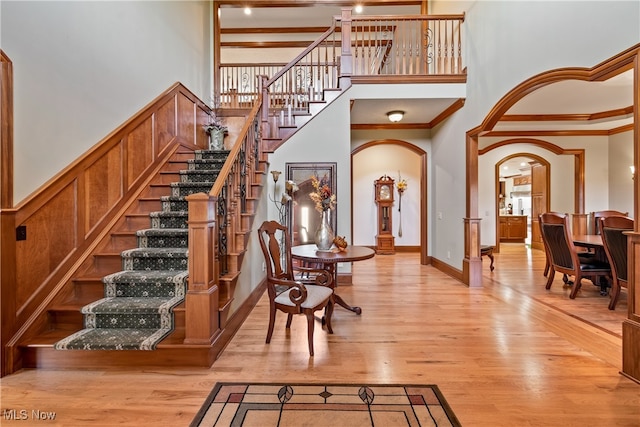 interior space featuring hardwood / wood-style flooring, a towering ceiling, and crown molding