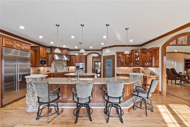 kitchen with built in appliances, a large island, and decorative light fixtures