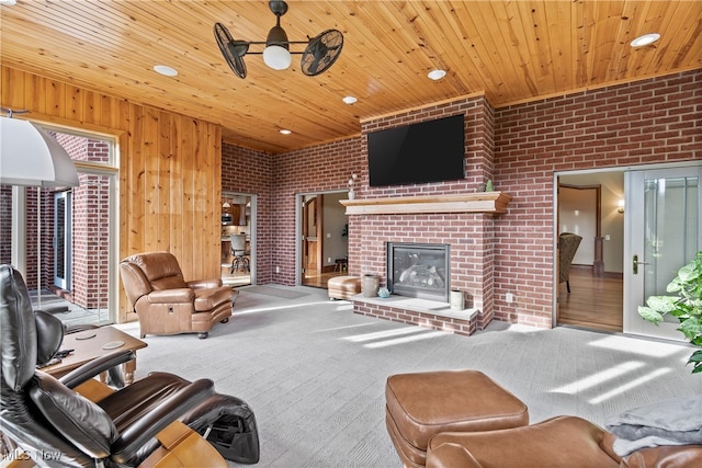 living room with carpet flooring, ceiling fan, brick wall, and a brick fireplace