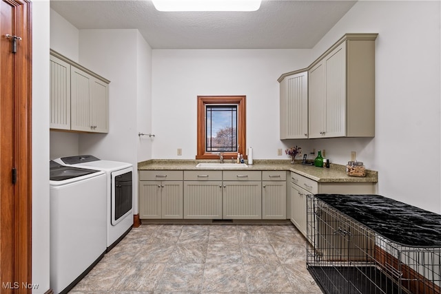 laundry area with a textured ceiling, cabinets, sink, and washing machine and dryer