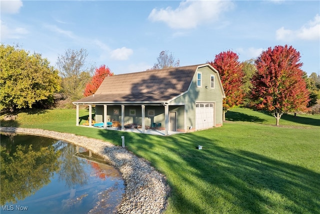 rear view of house featuring a lawn, a garage, and an outbuilding